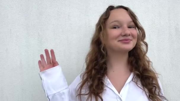 Menina Uma Camisa Branca Acenando Para Câmera Sorrindo Seguida Mostrando — Vídeo de Stock