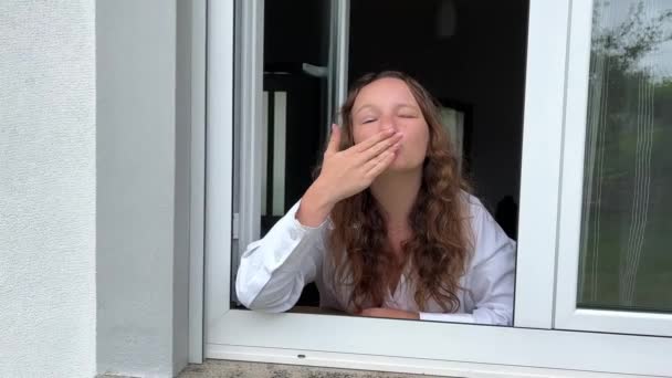 Una Adolescente Está Soplando Besos Desde Una Ventana Blanca Lleva — Vídeo de stock