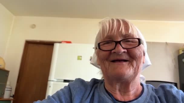 奶奶带着爱心准备饺子80年了 她是家里的守护神 她穿着一条白色的围巾和一件蓝色的夹克 坐在厨房里 做饺子和饺子 — 图库视频影像