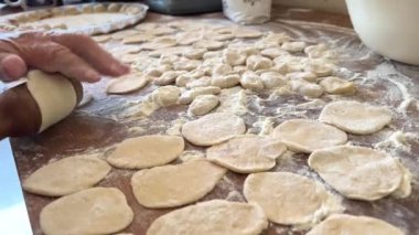  Hamur köftelerini heykeller ve ahşap bir masaya koyar, onlardan bir sürü vardır, unu iştah açıcıdırlar ve pişirilmeyi beklerler her hamur köftesi etle doludur, yuvarlaktır ve düzgünce el yapımıdır.