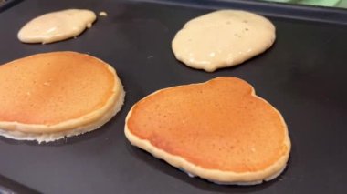 Siyah bir yüzeyde, Amerika 'da Kanada' da lezzetli krepler pişiriliyor ve siyah olanlar bir tarafta spatulayla çevrilmiş, diğer tarafta pişmemiş hamur var. Yüksek kalite 4k görüntü