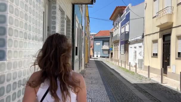 一名身穿白色T恤和牛仔裤戴墨镜的女孩走在葡萄牙瓦尔齐姆市的石街上 走在街道上 走在大自然的面前 高质量的4K镜头 — 图库视频影像