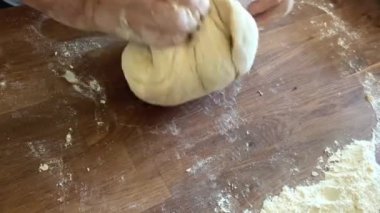Yaşlı bir kadının yaşlı elleri hamuru yuvarlar ve bir şeyler pişirir ya da hamur köftelerini ya da hamur köftelerini ahşap bir yüzeyde kaynatır. Yüksek kalite 4k görüntü