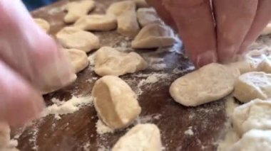 Yaşlı bir kadının yaşlı elleri hamuru yuvarlar ve bir şeyler pişirir ya da hamur köftelerini ya da hamur köftelerini ahşap bir yüzeyde kaynatır. Yüksek kalite 4k görüntü
