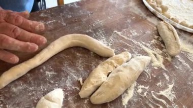Yaşlı bir kadının yaşlı elleri hamuru yuvarlar ve bir şeyler pişirir ya da hamur köftelerini ya da hamur köftelerini ahşap bir yüzeyde kaynatır. Yüksek kalite 4k görüntü