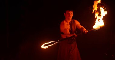 Circus fire show a man stands with fire, he is half-dressed against a dark background, the fire is burning right in front of the camera. High quality photo Ukraine Vinnitsa 15.01.2015