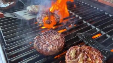 Barbekü pirzolaları çok lezzetli görünüyor. Izgarada açık ateşte bir hamburger için pişirilmiş. Her ateş yandığında bir spatulayla dönüşüyor ve her restoran için yavaş çekim videosu yaratıyor..
