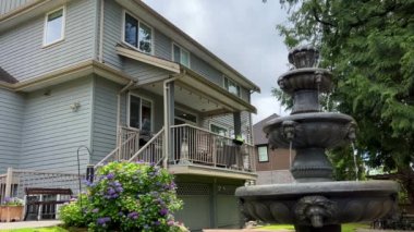 Canada city Surrey typical house in Canada a rich area in the courtyard of the house a fountain with clear water a house of beige gray color everything is in gentle colors nearby flowers grow
