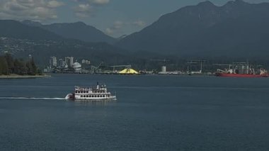 Beyaz bir motorlu tekne, Vancouver açıklarında Pasifik Okyanusu 'nu yavaş çekimde geçerek dağların ve mavi gökyüzünün arka planına doğru ilerler. 4k