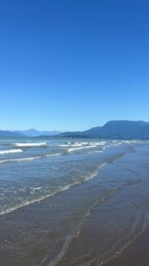 Wreck Beach, Tower Beach, Acadia Beach, Vancouver 'daki çıplaklar plajı. Kamera Pasifik Okyanusu' nda yavaşça döner ve Vancouver Adası 'nın mavi gökyüzü ve dikey sularının beyaz çizgilerini gösterir.