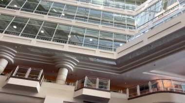 Inside Canada Place, the camera smoothly drives through beautiful windows, beige walls and various patterns on the walls Through the transparent glass ceiling can see the sky Canada Vancouver 07.2022.