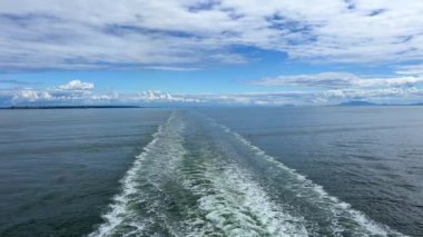 a trail on the water leaving itself a ship a huge liner a cruise ship you can see seething water beautiful sky deep ocean around nature and the ship is sailing away Canada to Vancouver Island Ferry