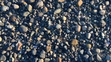 the camera slowly floats over the rocky beach of the Pacific ocean showing each stone for any background For the text of the advertisement music for relaxation Parksville beach Surfside RV resort.