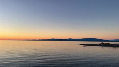 sunset on Pacific Ocean calm silhouette of man floating on the board Surfing in evening in hands of a man a paddle he is literally a point against the background of nature you can see the red oranges