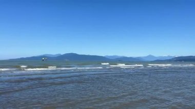 Wreck Beach, Tower Beach, Acadia Beach Nudist beach in Vancouver The camera slowly pans over Pacific Ocean showing small waves that form white stripes of Vancouver Island blue sky and water 