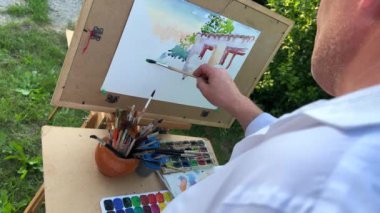 Drawing lesson the artist painted a picture and drank a cup of coffee He is wearing a white shirt Man 50-60 years old Ready video clip only to put music Leisure retired professional art