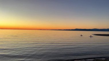 sunset on Pacific Ocean calm silhouette of man floating on the board Surfing in evening in hands of a man a paddle he is literally a point against the background of nature you can see the red oranges
