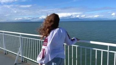Ukrainian women leave for other countries during the war resettlement to Canada girl in embroidered shirt walks along ship and looks sadly at the sea wind develops her hair Refugees On ferry on liner.