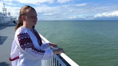 Ocean sea girl is standing alone on liner and is very happy she is returning home she fled from Ukraine war Now Ukraine has won she can return home to her parents IDPs and refugees return to Ukraine