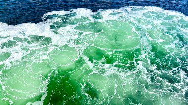 Abstract blue sea water with white foam for background Deep green ocean wave with mountain and sky in background Texture of green marble. High quality photo
