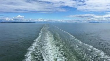 a trail on the water leaving itself a ship a huge liner a cruise ship you can see seething water beautiful sky deep ocean around nature and the ship is sailing away Canada to Vancouver Island Ferry