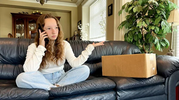 A teenage girl sits in a room and calls on phone she swears at stores from which the parcel was sent next to it there is a box on which you can make an inscription resents delivery was unsuccessful.