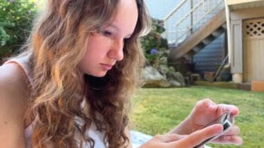 Sosyal ağlar çevrimiçi öğrenme, lise öğrencileri ve gençlerin hayatının ayrılmaz bir parçasıdır. Bir kız telefonda beyaz elbiseli beyaz bir battaniyenin üzerinde telefonda oturuyor.