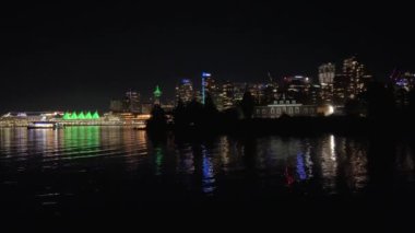 Kanada 'da karanlık bir gece. Vancouver manzarası. Okyanus manzarası. Kanada yeşil gökdelenlerle parıldıyor.