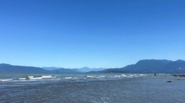 Wreck Beach, Tower Beach, Acadia Beach Nudist beach in Vancouver The camera slowly pans over Pacific Ocean showing small waves that form white stripes of Vancouver Island blue sky and water 