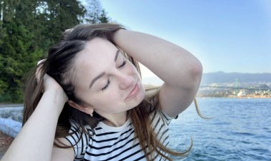 Okyanustaki genç kadın üzgün. Yüzünün bir kısmı şakayla somurtuyor. Yüzüne iki taraftan bastırıyor.