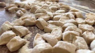 Yaşlı bir kadının yaşlı elleri hamuru yuvarlar ve bir şeyler pişirir ya da hamur köftelerini ya da hamur köftelerini ahşap bir yüzeyde kaynatır. Yüksek kalite 4k görüntü
