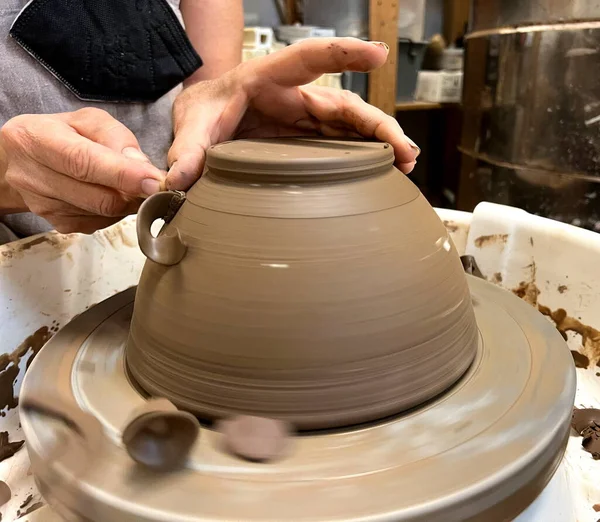 Potters master class Pottery wheel the art of making pottery for kitchen utensils Womens hands cut off excess clay shavings are visible as if from chocolate Flowing from falling like Serpentine