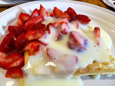 Kremalı çilekler waffle üzerine uzanmış lezzetli iştah açıcı tatlı kamera yukarıdan çekerken yavaşça yüzüyor.