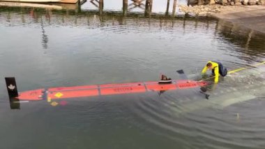 Eski değirmen kayıkhanesinde kürek çeken yelken merkezi liman kenli Esplanade Bulvarı Rocky Point Park Eğlence İskelesi Su geçirmez takım elbiseli bir adam Pasifik Okyanusu 'ndan bir denizaltıyı çıkardı