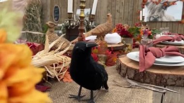 Masada ahşap tezgahlarda tabaklar çatal bıçaklar ve bardakların yanında kırmızı ve siyah mısır başları ortada kırmızı peçeteler her şey Cadılar Bayramı için hazırdır Ekim akşamı Cadılar Bayramı için akşam yemeği 
