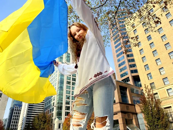 teenager covers the camera with a flag flashing yellow and blue embroidered Ukrainian shirt is dancing and spinning with the flag of Ukraine Victory she is happy to return to the Ukrainian land