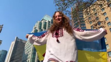 Genç kız, Ukrayna bayrağıyla dans eden ve dönen sarı ve mavi işlemeli bir Ukrayna gömleğiyle kamerayı kapatıyor. Ukrayna topraklarına dönmekten mutlu.