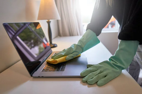 Sanitizing laptop at home. disinfecting laptop with gloves on. cleaning office