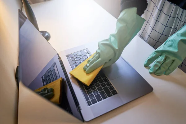 Sanitizing laptop at home. disinfecting laptop with gloves on. cleaning office