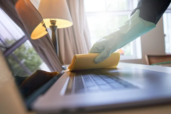 Sanitizing laptop at home. disinfecting laptop with gloves on. cleaning office