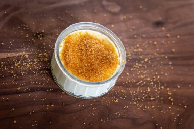 Krema tabağı. Fransız tatlısı. Tahta bir yüzeyde cam bir kaseye şeker serpiştirilmiş.