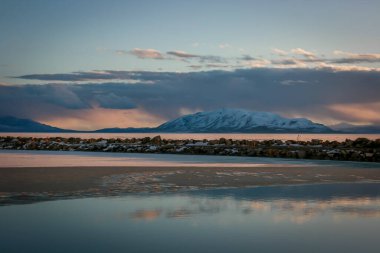 Gün batımında buzla kaplı göl ve uzaktaki dağ