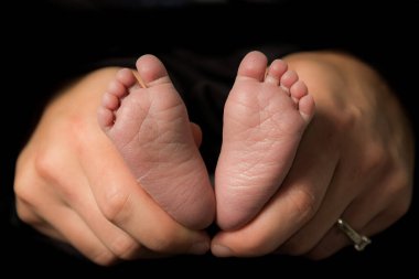 Annenin elleri bebeğin ayaklarını tutuyor.