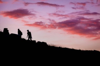 Yürüyüşçüler gün batımında tepeye tırmanıyor