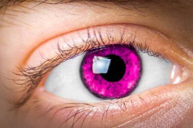 Extreme close up a girl's eye that is colored magenta and looking at the camera