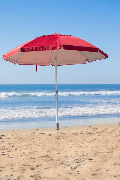 Kumsaldaki kırmızı plaj şemsiyesi