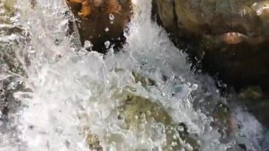 Ağır çekimde akan ve kayaya çarpan berrak bir dağ nehrinin yavaş akışı.