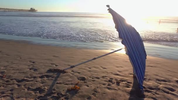 Una Sombrilla Playa Lado Una Playa Contra Una Puesta Sol — Vídeo de stock