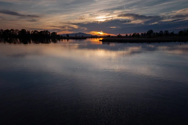 Una Puesta Sol Colorida Con Cielo Nublado Que Refleja Superficie — Foto de Stock