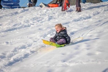 Tepenin yamaçlarında kar yağarken gülümseyen tatlı küçük kız.